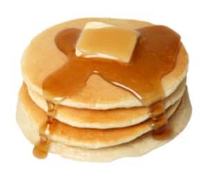 Stack of fluffy pancakes with syrup and butter, served with sausage.